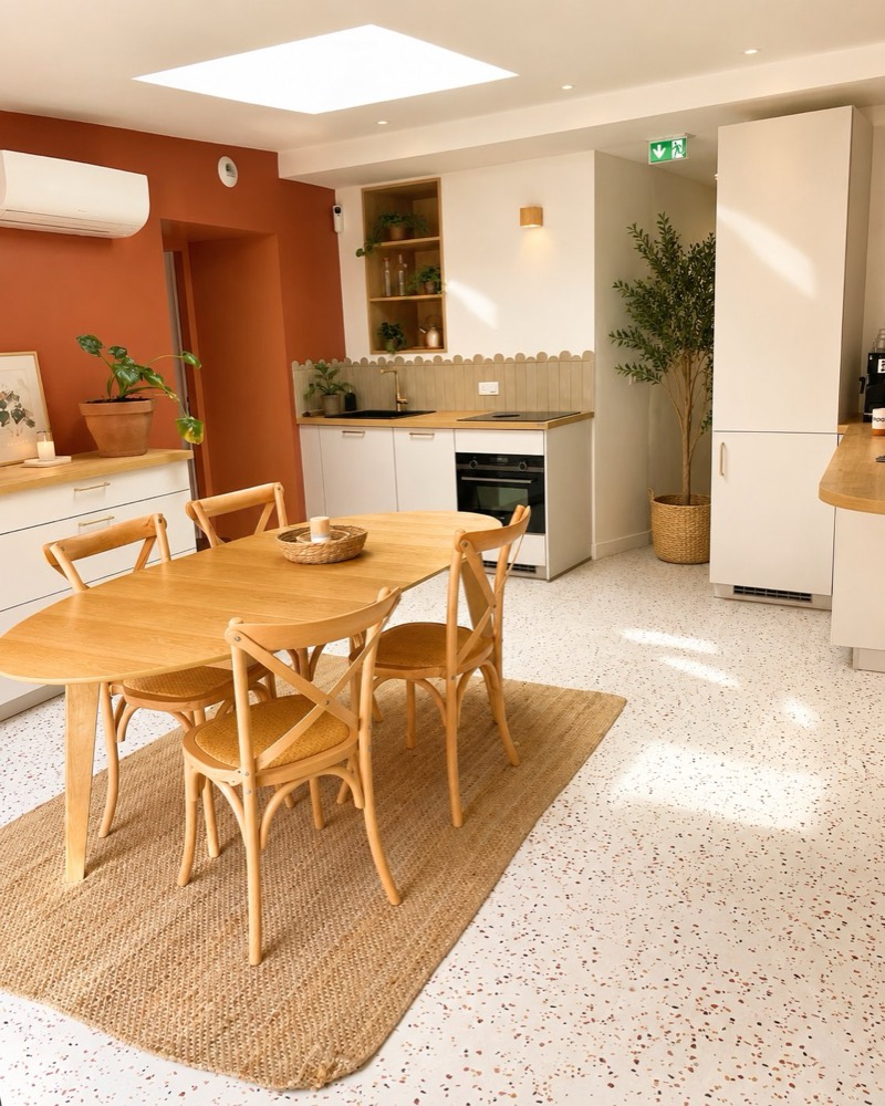 La cuisine partagée : table en bois, chaises bistrot et mur terracotta
